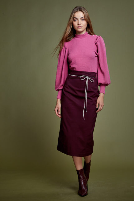 דוגמנית מציגה לוק צנוע של חצאית מידי צנועה בצבע בורדו וחולצה חגיגית בצבע ורוד