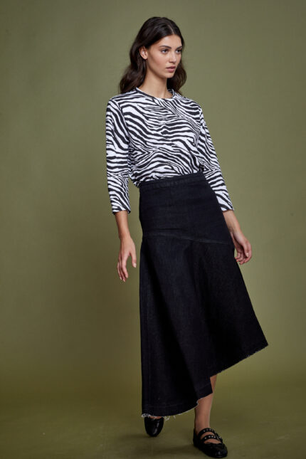 דוגמנית מציגה חצאית ג'ינס צנועה בגזרה אסימטרית בגוון שחור