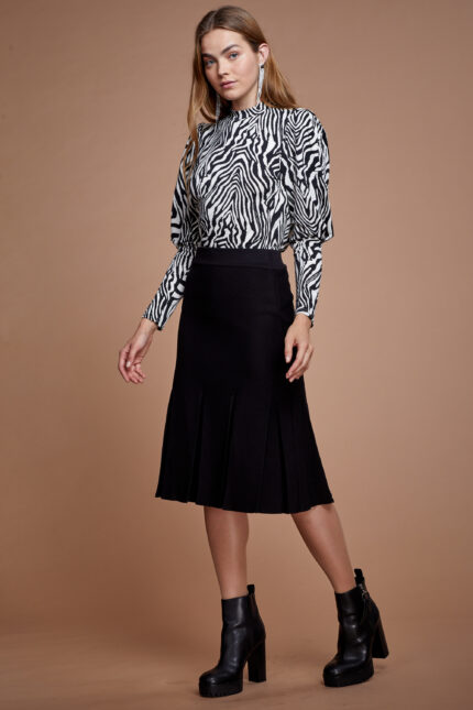 דוגמנית מציגה חצאית סריג צנועה בצבע שחור עם וולאן פתיחה בסיומת החצאית