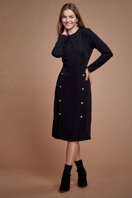 דוגמנית לובשת שמלה צנועה בצבע שחור עם כפתורי זהב