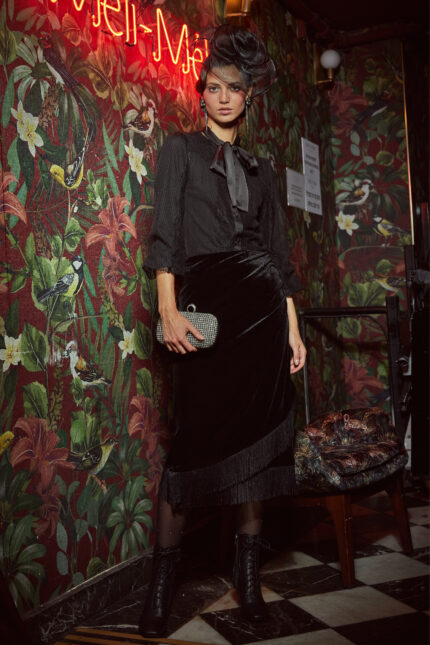 דוגמנית מציגה לוק צנוע של חצאית צנועה לערב לנשים ומידות גדולות צבע שחור סיומת פרנזים