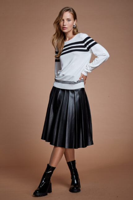 דוגמנית מציגה לוק צנוע של חצאית דמוי עור מתרחבת וסריג פסים שחור לבן