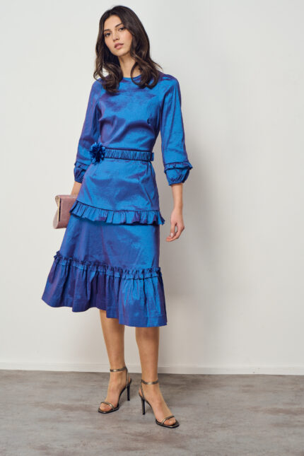 דוגמנית מציגה שמלה לאירוע בגוון כחול מבריק עם קומות וולאן