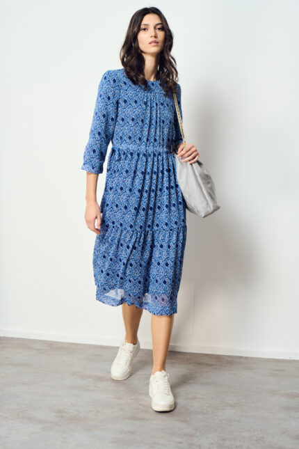 דוגמנית מציגה שמלה צנועה מתרחבת עם חגורת מסילה במותן בגווני כחול